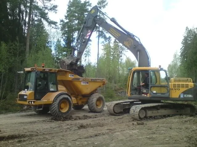 Grävmaskin som lastar sten bredvid en dumper